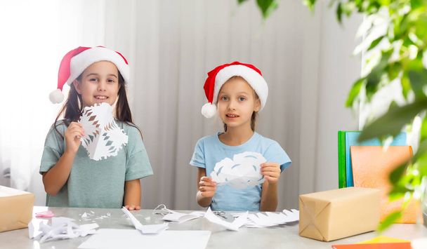 dos niñas cortar copos de nieve para la Navidad - Foto, imagen