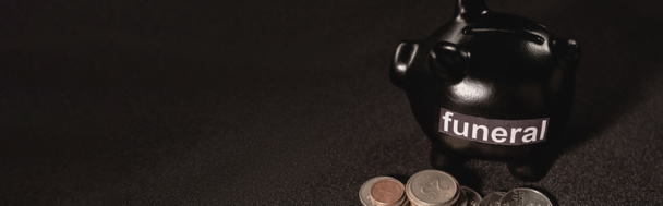 piggy bank with coins on black background, funeral concept, banner - Fotó, kép
