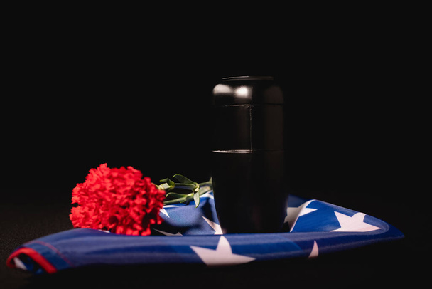 κόκκινη γαρύφαλλο, στάχτες και αμερικανική σημαία σε μαύρο φόντο, έννοια κηδεία - Φωτογραφία, εικόνα