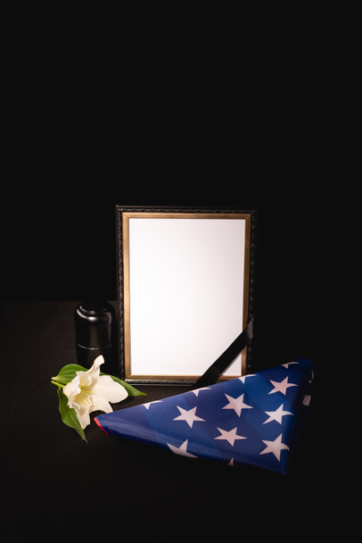 lily, mirror, ashes and american flag on black background, funeral concept - Фото, изображение