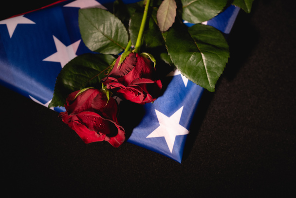 rosas rojas y bandera americana sobre fondo negro, concepto funerario - Foto, imagen