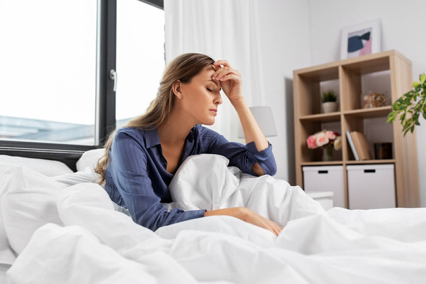 sleepy or stressed woman sitting in bed at home - Φωτογραφία, εικόνα