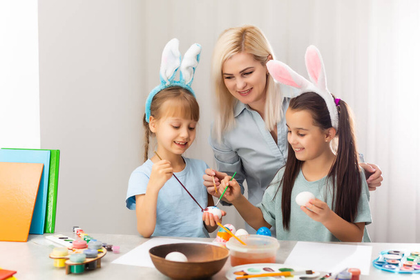 Nuori äiti ja hänen kaksi tytärtään maalaavat pääsiäismunia - Valokuva, kuva