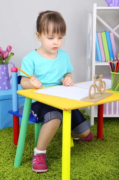 Little girl draws sitting at table in room - Фото, зображення