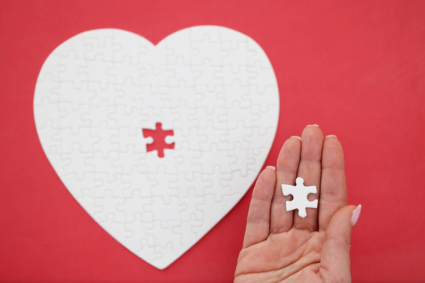 Womans hand holding last piece from puzzles in shape of heart close-up - Φωτογραφία, εικόνα
