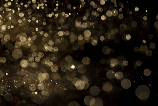 The shiny golden bokeh lights on a black background - 写真・画像