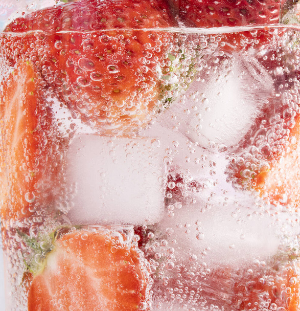 A closeup shot of strawberries and ice in sparkling water - Photo, Image