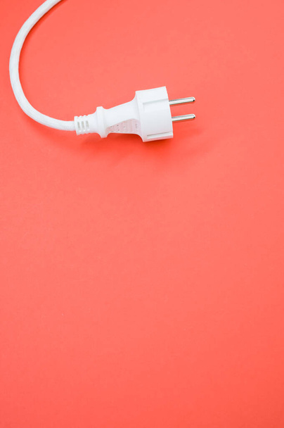 Vertikální záběr elektrického drátu a zástrčky na růžovém povrchu - Fotografie, Obrázek