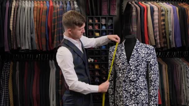 Zpomalený pohyb krejčího v vestě při měření centimetrem pro nový ručně vyrobený oblek vysoké kvality v ateliéru nebo luxusním obchodě - Záběry, video