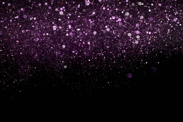 A beautiful, sparkling purple glitter pouring down from above on a dark background - Foto, Bild