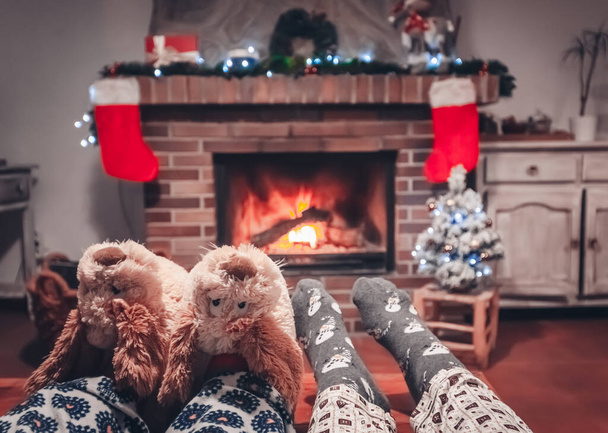 A couple relaxing by the warm fire in woolen socks - holidays concept - Zdjęcie, obraz