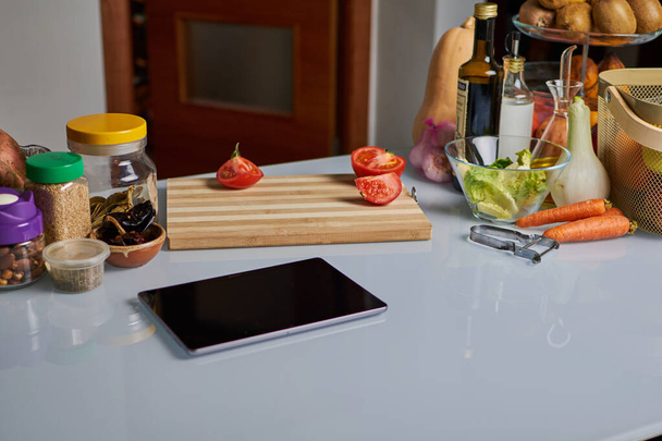 Friss nyers zöldségek, fűszerek és egy tabletta a konyhaasztalon - Fotó, kép