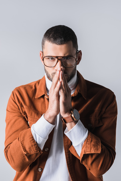 Stylish man in eyeglasses with prayer hands looking at camera isolated on grey  - Valokuva, kuva