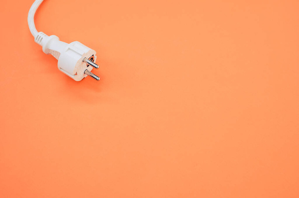 A high angle shot of an electrical wire and plug on an orange surface - Фото, изображение