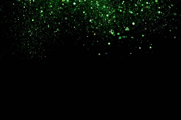 A beautiful, sparkling green glitter pouring down from above on a dark background - Photo, Image