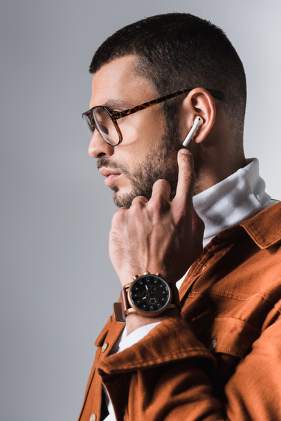 Bearded man pointing with finger at wireless earphone on grey background  - Φωτογραφία, εικόνα