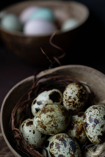 A vertical shot of speckled quail eggs with jute twine in a rustic bowl - Fotoğraf, Görsel