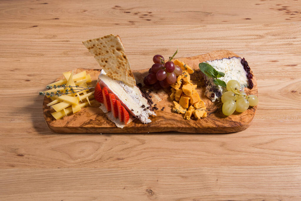 Varios tipos diferentes de rebanadas de queso, mezcla de queso en la tabla de cortar de madera. Snack de vino. Camembert, parmesano, queso brie. - Foto, Imagen
