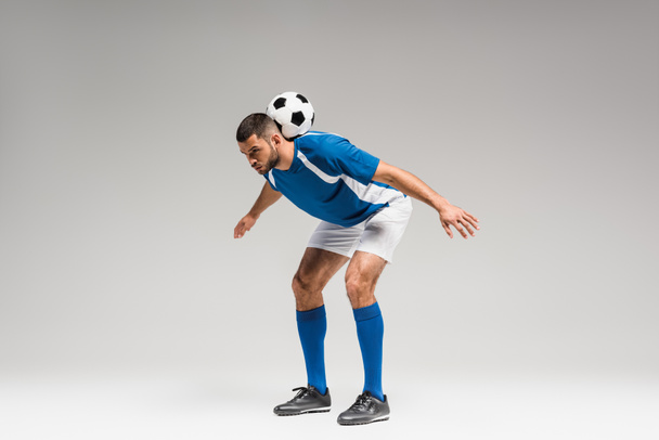 Sportsman in sportswear holding football on back on grey background  - Fotoğraf, Görsel