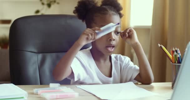 Nettes lustiges Vorschulmädchen afroamerikanisches Kind lernt, mit farbigen Markern zu malen, während es während der Coronavirus-Pandemie fernab von zu Hause online mit dem Zeichenlehrer kommuniziert - Filmmaterial, Video