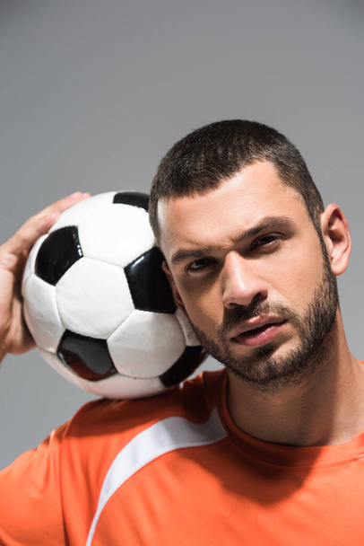 Portrait of bearded sportsman looking at camera near football on blurred background isolated on grey - Fotó, kép