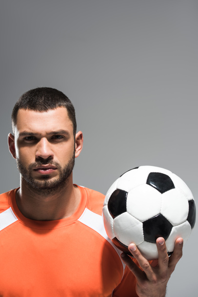 Football in hand of young sportsman isolated on grey - Фото, зображення