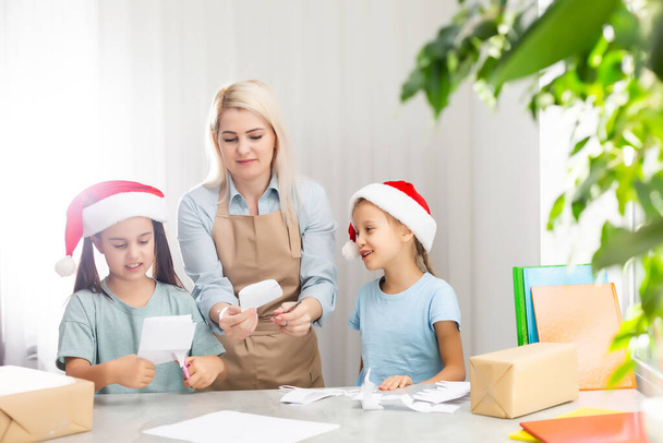 Jovem mulher ajudando filhas pequenas para fazer decoração para o Natal - Foto, Imagem