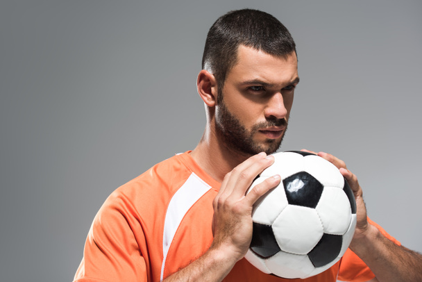 Desportista sério em sportswear segurando futebol isolado em cinza - Foto, Imagem