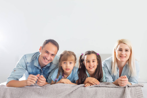 Ευτυχισμένη οικογένεια παίζει μαζί σε ένα κρεβάτι στο σπίτι - Φωτογραφία, εικόνα