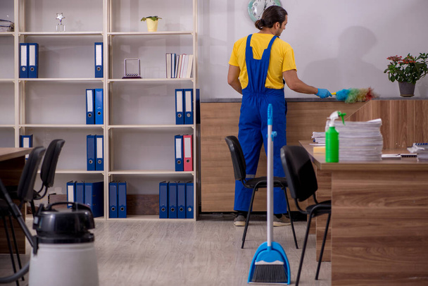 Joven contratista masculino limpiando la oficina - Foto, Imagen