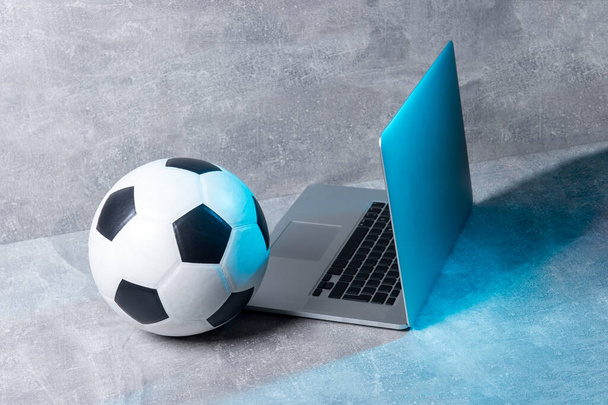 Футбольний та футбольний м'яч та сірий ноутбук на сірому фоні. Концепція онлайн-тренувань
 - Фото, зображення