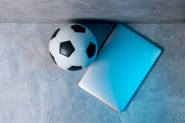 Soccer and football ball and grey laptop on grey background. Online workout concept - Foto, imagen