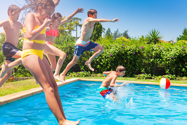 Boys and girls in a group jump in water pool outside during summer vacation - Foto, imagen