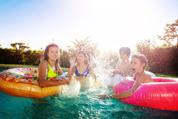 Many children friends with inflatable rings splash in swimming pool playing together having fun - Foto, Imagem
