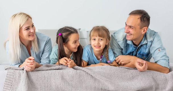 Szczęśliwa rodzina bawiąca się razem na łóżku w domu - Zdjęcie, obraz