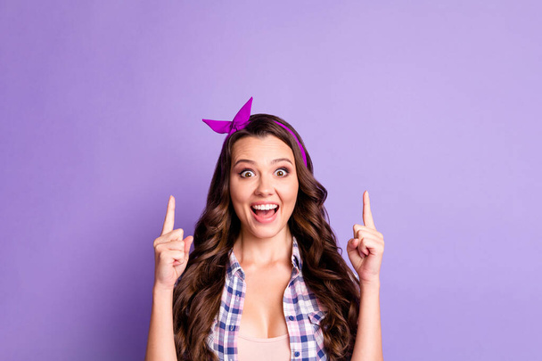 Zdjęcie podekscytowany dziewczyna punkt wskazujący palec w górę copyspace nosić koszulę kratę izolowane na fioletowy kolor tła - Zdjęcie, obraz