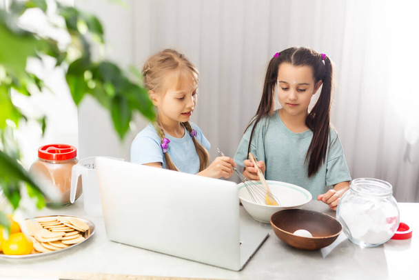 dwie dziewczyny uczą się gotować na laptopie online, oglądanie wideo, uśmiech - Zdjęcie, obraz