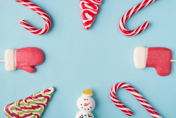 Christmas composition concept. Top above overhead close up view photo of different yummy candies lying on table with blank empty space in center isolated pastel background - Foto, immagini