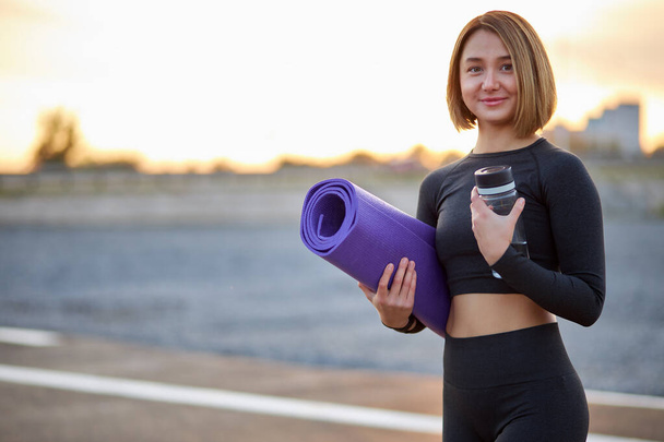 portrait of good-looking caucasian woman with water bottle in city, enjoy workout outdoors - Photo, Image