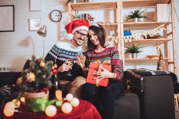 Jovem casal celebrando o Natal em casa abre presente - Foto, Imagem