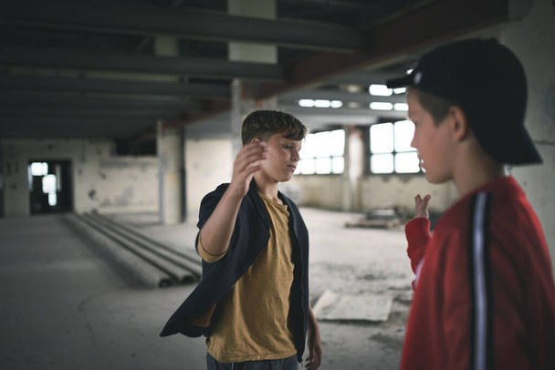 Teenagers boys indoors in abandoned building, greeting. - Photo, image