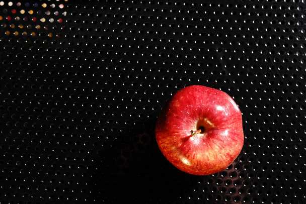 Red Apple on a black background. Half-light and a brightly lit Apple. - Foto, imagen