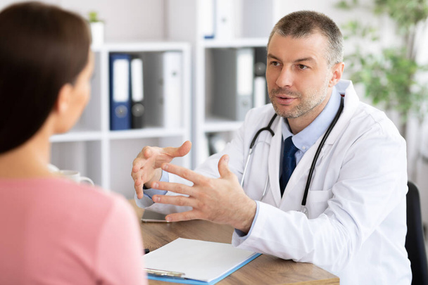 Médico experimentado de mediana edad hablando con su paciente - Foto, Imagen