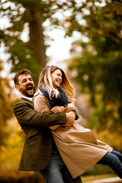 秋の公園で楽しんでいるハンサムな若いカップル - 写真・画像