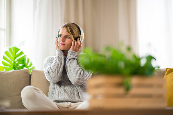 Portrait of woman with headphones relaxing indoors at home, mental health care concept. - Фото, зображення