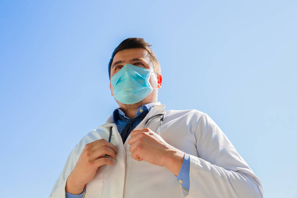 Doctor en máscara médica al aire libre. Tratamiento durante la pandemia de coronavirus. - Foto, Imagen