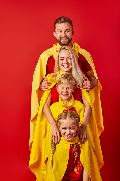 super family in cloaks standing isolated on red background - Valokuva, kuva