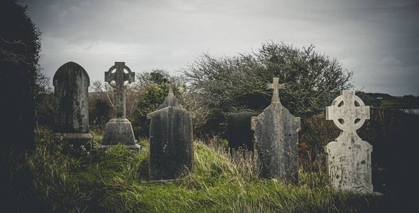 Írország kelta kereszt a középkori templom temetőjében Régi kísérteties temető. Kísértetjárta temető. Ijesztő hely. Régi sírok - Fotó, kép