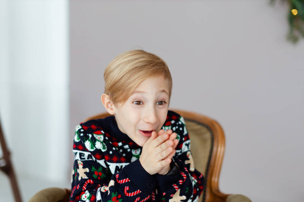 portrait of a child in a Christmas sweater makes funny faces - Photo, Image