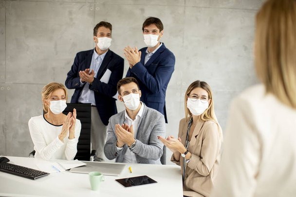 Üzletemberek csapata, akik arcmaszkos projekten dolgoznak vírusvédelemként az irodában. - Fotó, kép